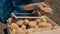 farmer sits on the ground with a harvest of potatoes and works in a tablet, touching display of gadget with finger