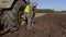 Farmer sitting near tractor wheel and talking on phone