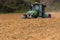 A farmer sowing with a John Deere tractor