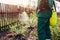 Farmer spraying tree with manual pesticide sprayer against insects in spring garden. Agriculture and gardening