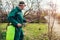 Farmer spraying tree with manual pesticide sprayer against insects in spring garden. Agriculture and gardening