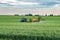 Farmer spraying wheat field with tractor sprayer at spring season