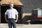 Farmer Standing In Front Of Farm Buildings