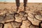 Farmer standing on parched landscape.