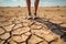 Farmer standing on parched landscape. Drought, disaster and crop failure.