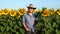 Farmer standing in sunflower field examining crop, looking at camera