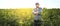 A farmer stands against the background of an agricultural field of sunflowers, selective focus, panorama