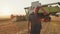 farmer stands against the background of a wheat field and a combine harvester,