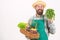 Farmer straw hat hold parsley and basket vegetables. Fresh organic vegetables wicker basket. Hipster gardener wear apron