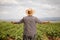 Farmer with a straw hat looking at a grapevine field