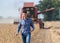 Farmer with tablet in front of combine harvester in soybean field