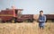 Farmer with tablet in front of combine harvester in soybean field