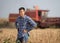 Farmer with tablet in front of combine harvester in soybean field