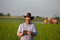 Farmer with tablet in front of tractor in field