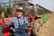 Farmer with tablet standing beside tractor in orchard