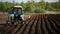 Farmer in tractor and birds preparing land for sowing.Back view