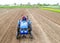 A farmer on a tractor carries out land work by milling and grinding the soil and removing roots after last harvest. Loosening