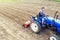 A farmer on a tractor cultivates a farm field. Grinding and loosening soil, removing plants and roots from past harvest. Field