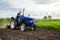 Farmer on tractor cultivates farm field. Milling soil, crushing and loosening ground before cutting rows. Farming, agriculture