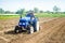 A farmer on a tractor cultivates a farm field. Soil milling, crumbling and mixing. Loosening the surface, cultivating the land for