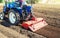 Farmer on a tractor cultivates land after harvesting. Grinding loosening plowing crumbling soil for further sowing by cultivated