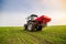 Farmer in tractor fertilizing wheat field at spring with npk