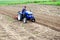 Farmer on a tractor loosens soil with milling machine. Plowing field. First stage of preparing soil for planting. Loosening