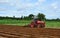 Farmer in tractor plowing land with red tractor for agriculture