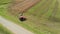 Farmer on a tractor with a reverse plow in a field near an asphalt road