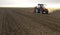 Farmer with tractor seeding crops at field