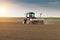 Farmer with tractor seeding - sowing crops at agricultural field