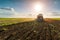 Farmer with tractor seeding - sowing crops at agricultural field