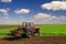 Farmer with tractor sowing on agricultural fields in spring