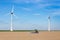 Farmer on tractor sowing in soil near and windmills