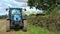 Farmer in a tractor using a flail hedge cutter on the edge of a field. UK