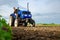 A farmer on a tractor works the field. Milling soil, crushing and loosening ground before cutting rows. Land cultivation. Farming