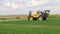 Farmer using a self propelled crop sprayer in a field in early spring.