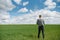 Farmer walking through a green wheat field on windy spring day and examining cereal crops