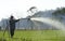 Farmer watering chive farm with hose sprinkle spray spatter