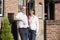 Farmer And Wife Standing In Front Of Farmhouse