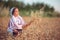 Farmer woman bulgarian little girl in ethnic folklore costume hold golden wheat straws and sickle in harvest field, harvesting and