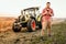 Farmer working and harvesting using smartphone in modern agriculture - tractor background