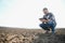 The farmer works on the ground. Male farmer on a plowed field, planting cereals in the spring in the ground