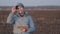 a farmer works in a tablet and smiles, a plowed field ready for sowing a crop, farming, a happy agronomist makes a count