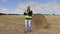 Farmer writing on the field near straw bales