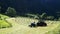 Farmers are baling freshly mown hay in field and wrapping the round bale by rotating it in white plastic using a machine attached