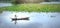 Farmers carrying lilies boating through rural marshland in early morning