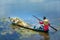 Farmers carrying lilies boating through rural marshland in early morning