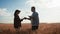 Farmers handshake over the wheat crop in harvest time. Team farmers stand in a wheat field with tablet. Partnership