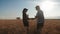 Farmers handshake over the wheat crop in harvest time. Team farmers stand in a wheat field with tablet. Partnership